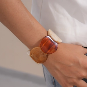 Detailed view of translucent amber and beige acrylic resin bracelet worn on a wrist