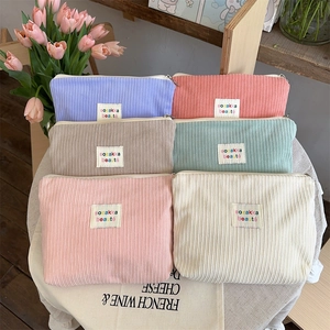 Various colors of corduroy cosmetic bags with labels arranged on a table