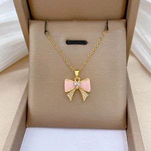 Macro shot of pink bow pendant with heart zircon and diamond inlay on gold chain