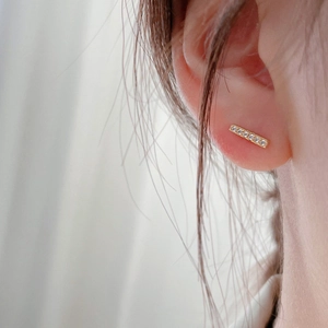 Close-up of elegant gold bar stud earrings with sparkling cubic zirconia on a model
