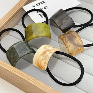 Close-up of five hair ties with marble-textured acrylic pieces in assorted earth tones