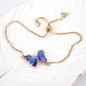 Detailed shot of gold adjustable bracelet with blue crystal butterfly and zircon stones