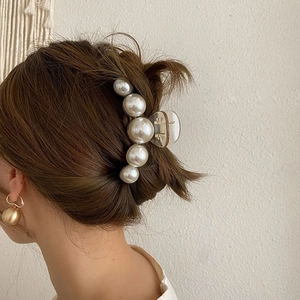 Detail view of large pearl hair claw clip worn by a model for elegant back hair styling