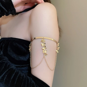 Close-up of golden butterfly arm cuff with tiered fringe chains on a female model
