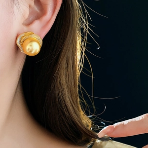 Close-up of a floral pearl earring with zircon inlays worn on a model's ear