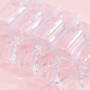 Mini transparent candy shaped storage boxes for jewelry on a pink background