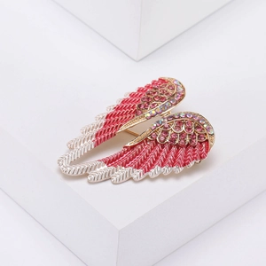Detailed view of angel wing brooch with pink rhinestones and fuchsia accents on alloy