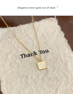 Detail of square mother of pearl pendant with yellow smiley face on golden chain necklace