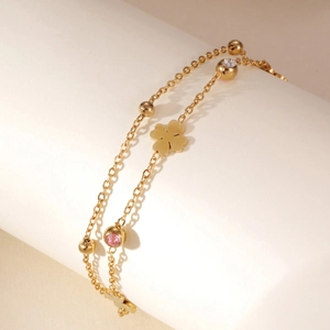 Detail of a 18K gold-plated double-layer bracelet with clover charms and pink crystals