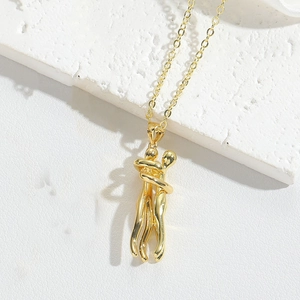 Close-up of golden necklace featuring a minimalist pendant of two figures embracing