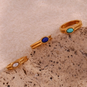 Three 18K gold plated stainless steel rings with turquoise and lapis on beige rock