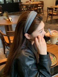 Detail of dark gray wide fabric headband on model in cozy cafe setting style