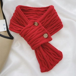 Detail of red cable knit scarf featuring two wooden buttons on a soft white fabric background