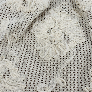 Cream knit slouchy beanie featuring detailed lace floral patterns and hollow texture
