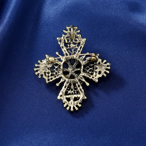 Golden vintage cross brooch with hollow metalwork on dark blue satin background
