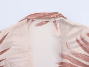 Detail of V-neck collar on sheer pink chiffon blouse with tropical plant leaf pattern