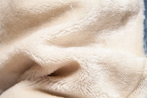 Macro detail of soft cream faux fur lining inside a blue denim jacket for warmth