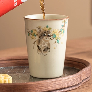 Ceramic Ru kiln tea cup with cat and floral patterns being filled with tea on wooden tray