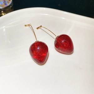 Vue macro de boucles d'oreilles fraise rouges avec paillettes dorées et crochets