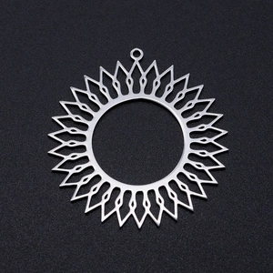 Detailed macro view of silver stainless steel sunburst pendant on a black matte surface