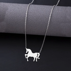 Silver horse pendant necklace on textured grey cylinder with black background