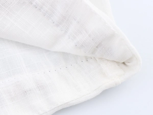 Close-up of fine stitching and natural cotton-linen texture on a white V-neck shirt