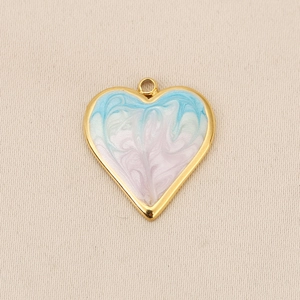 Macro detail of heart-shaped gold pendant with colorful marble enamel inlay on fabric
