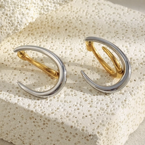 Macro detail of two-tone C-shaped hoop earrings on natural stone for jewelry display
