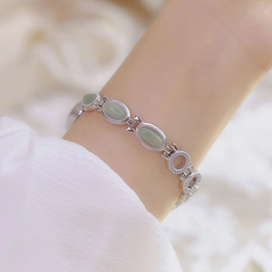 Detailed view of a silver bracelet watch with oval green jade stones on a wrist