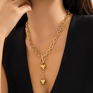 Close-up of golden OT buckle necklace with double heart pendants on a model