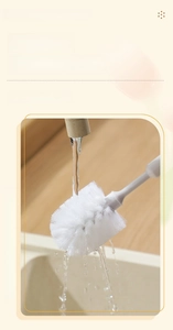 Macro view of water rinsing the dense fiber bristles of a white bottle cleaning brush