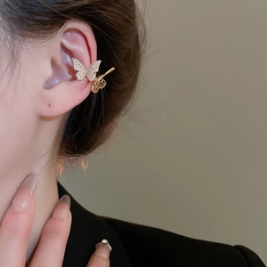 Close-up of a gold hollow butterfly ear cuff with sparkling zircons on a model's ear