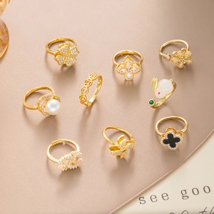 Luxurious 9-piece gold-plated ring set featuring clover and pearl charms on beige leather