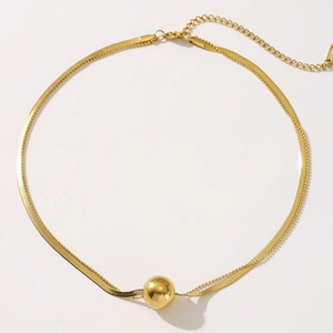 Detail of double-layer gold necklace featuring snake chain and polished ball pendant