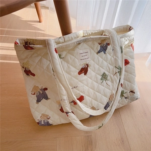 Detail of diamond quilted tote bag featuring cute bear prints and a woven French label