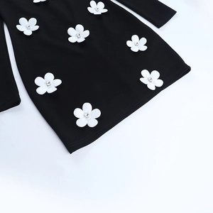 Détail d'appliqués de fleurs 3D avec cristaux sur le tissu d'une robe noire à manches