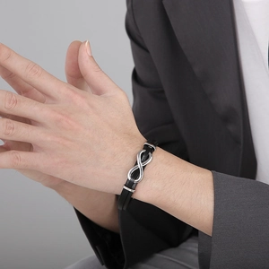 Detail of men's black braided leather bracelet with infinity symbol on model's wrist