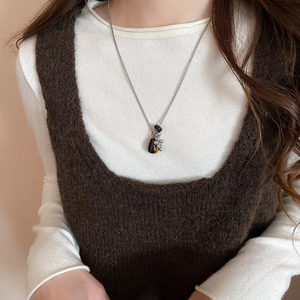 Detail of tiger eye stone pendant with silver beaded tassels on a layered sweater chain