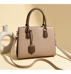 Close-up of khaki and brown leather tote bag with gold hardware and top handles