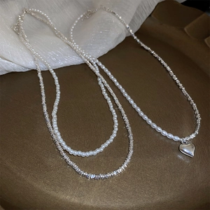 Detail of double-layer necklace with white pearls, silver beads and heart pendant