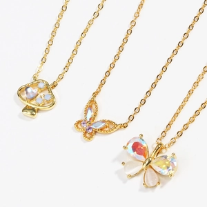 Three gold-plated necklaces with butterfly and mushroom opal pendants on white background