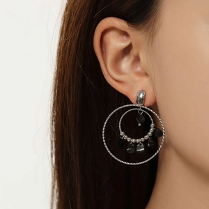 Detailed shot of double silver hoops and black bead charms on model’s ear