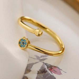 Detail of gold open ring with turquoise stone inlay on a luxury fabric background