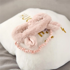 Cute pink plush rabbit eye mask for sleeping on a soft white pillow in a home setting