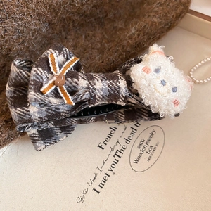 Detailed shot of plush bear on brown plaid bow hairpin with pearls and tweed background