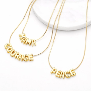 Gold-plated letter necklaces featuring MAMA COURAGE and PEACE pendants on snake chains