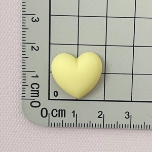 Close-up of a matte yellow resin heart bead on a measuring mat showing 1.5 cm size