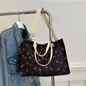 Black canvas tote bag with red cherry prints, dual handles and extra outer pockets