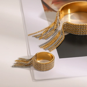 Detailed shot of gold and silver beaded tassel cuff bracelet and matching open ring set