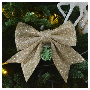 Close-up of golden glitter bow ornament hanging on a lush green Christmas tree branch